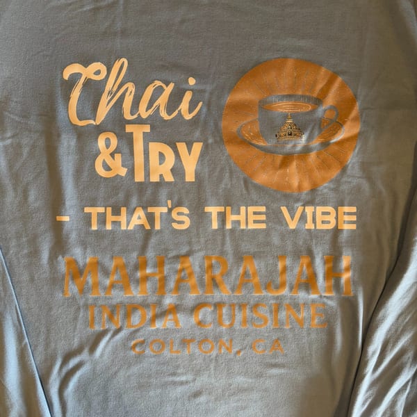Light blue t-shirt with orange text: "Chai & Try - That's the Vibe Maharajah India Cuisine Colton, CA"