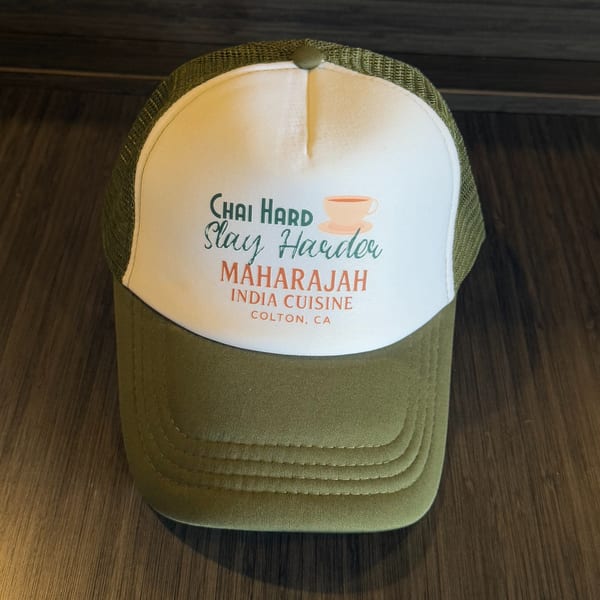 Maharajah India Cuisine branded hat with "Chai Hard Slay Harder" text and a chai cup graphic.