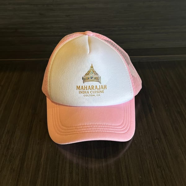 Pink and white Maharajah India Cuisine trucker hat with a gold crown logo.