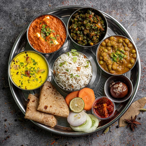 A Maharajah India Cuisine thali with various curries, rice, flatbread, dessert, and condiments.