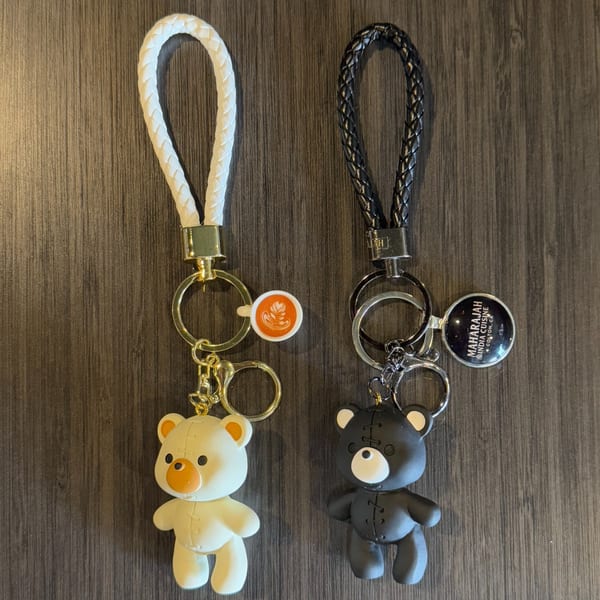 Two teddy bear keychains, one white and one black, with Maharajah India Cuisine branding.