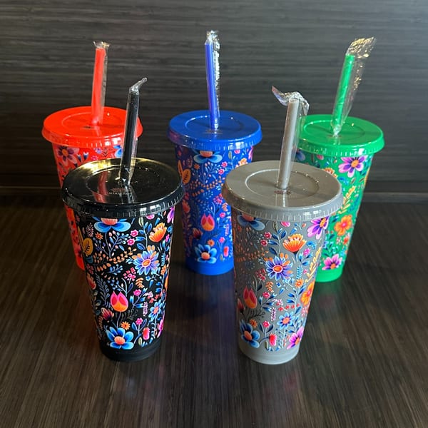 Five colorful tumblers with floral designs and straws, ready for beverages at Maharajah India Cuisine.